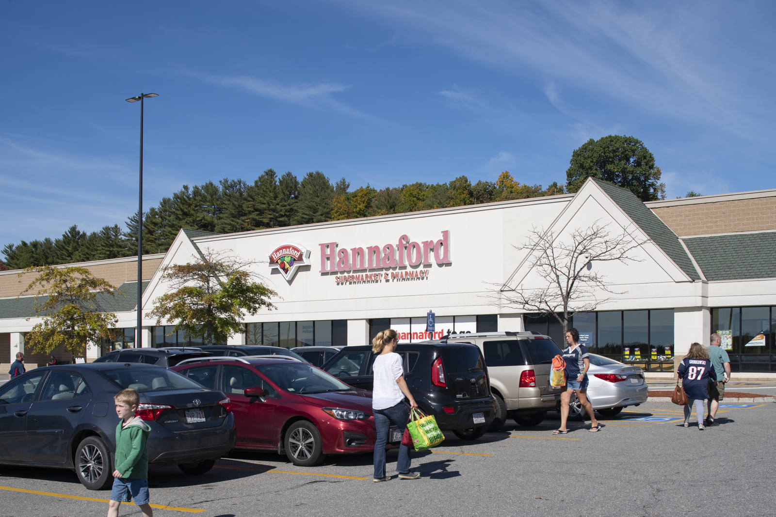 Shoppers with bags walking parking lot at Hannaford Supermarket in Lunenburg, MA.