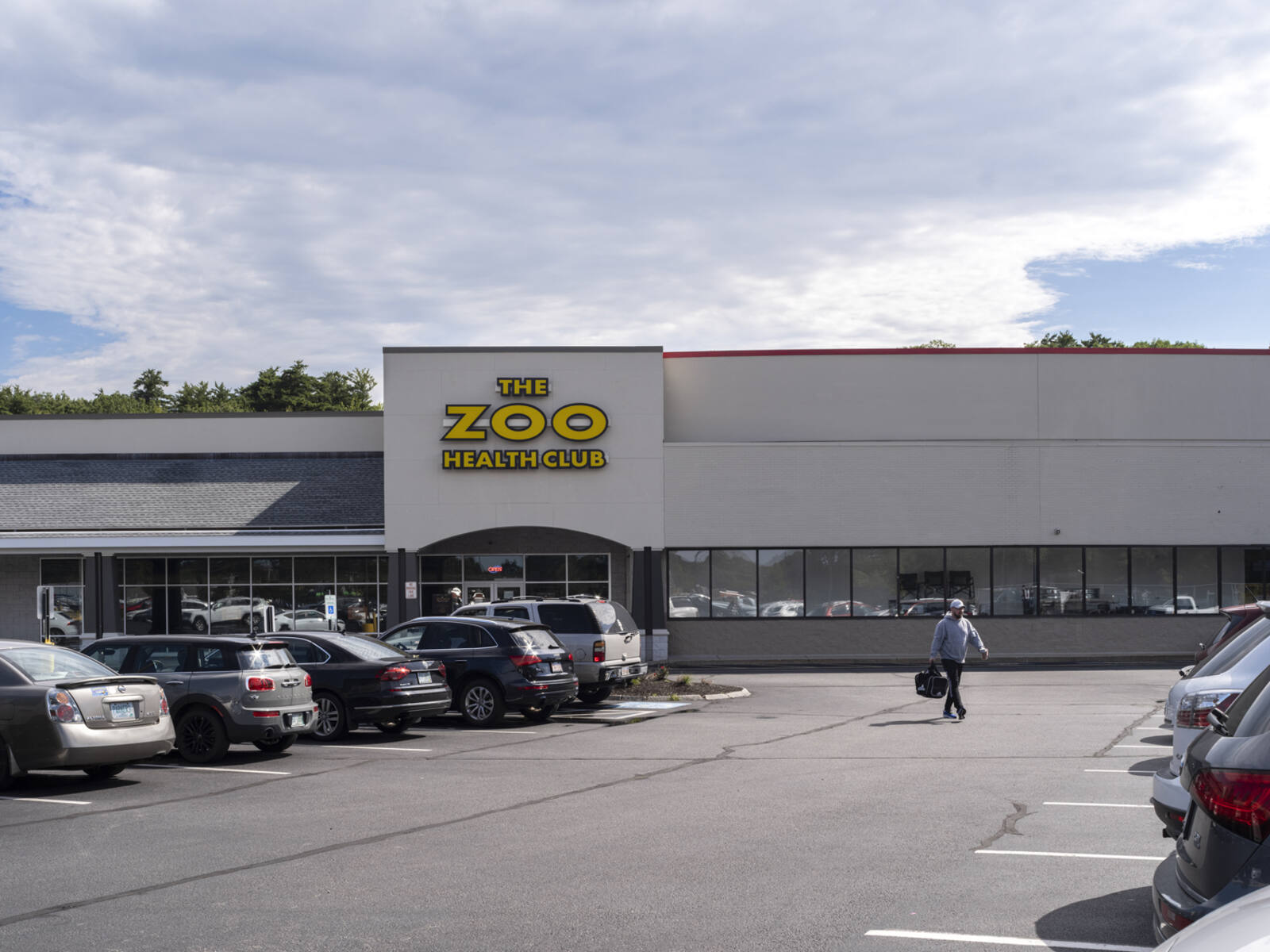 Man walks through busy parking lot The Zoo Health Club.