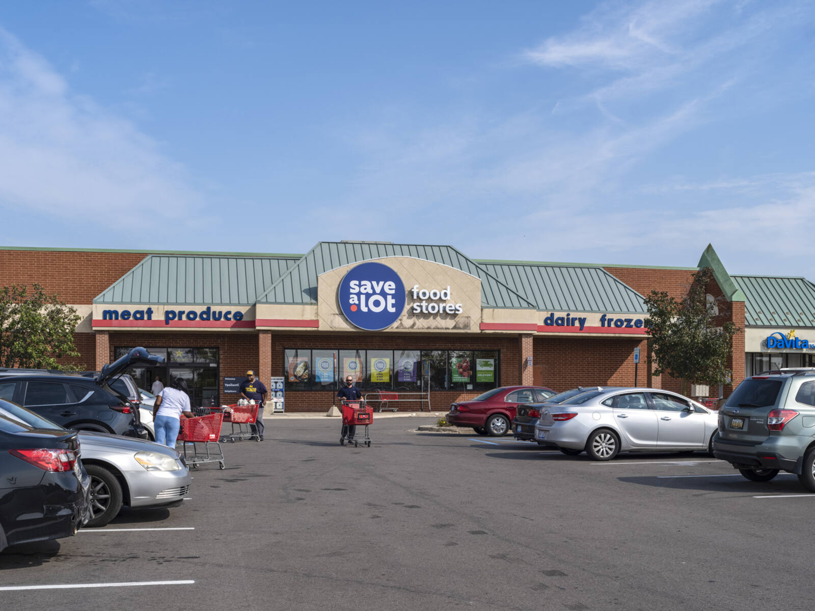 Save A Lot grocer with buys parking lot and customers unloading carts into cars.