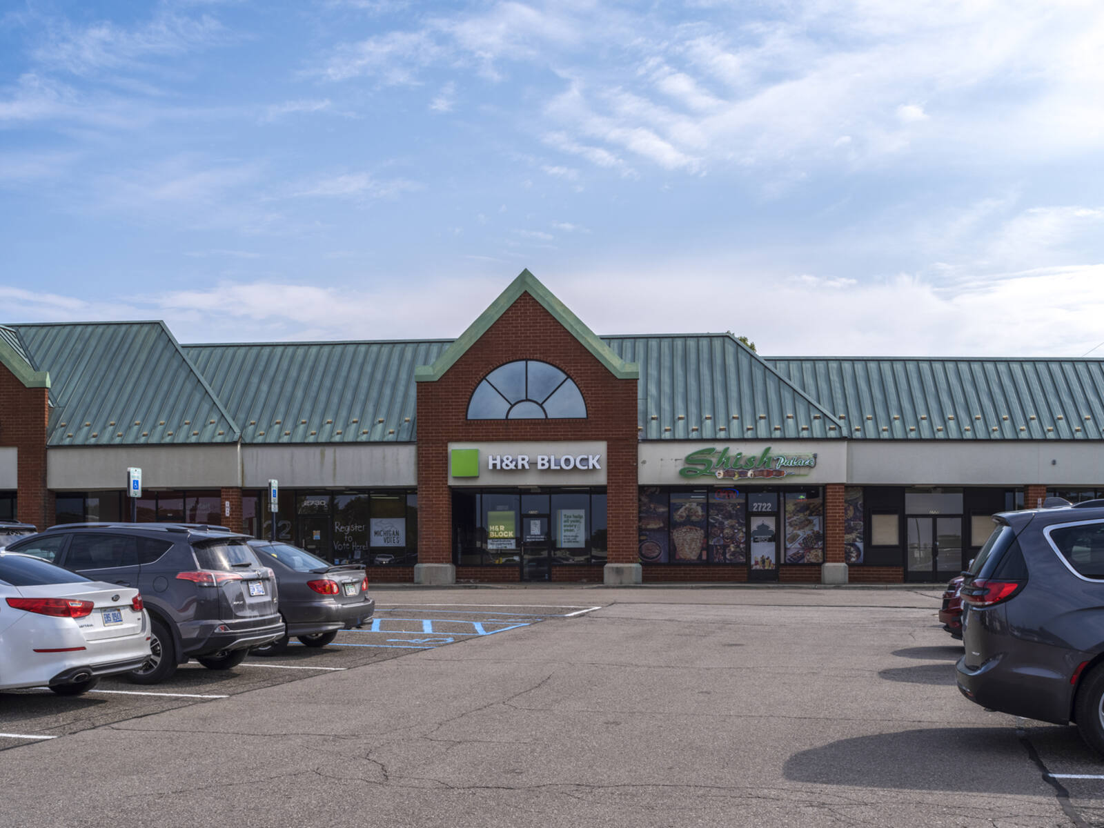 Busy parking lot with inline shops like HR Block.
