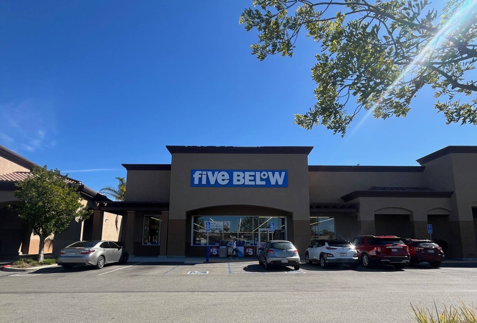 Five Below with tree limb overhanging in sunbeam on the right.