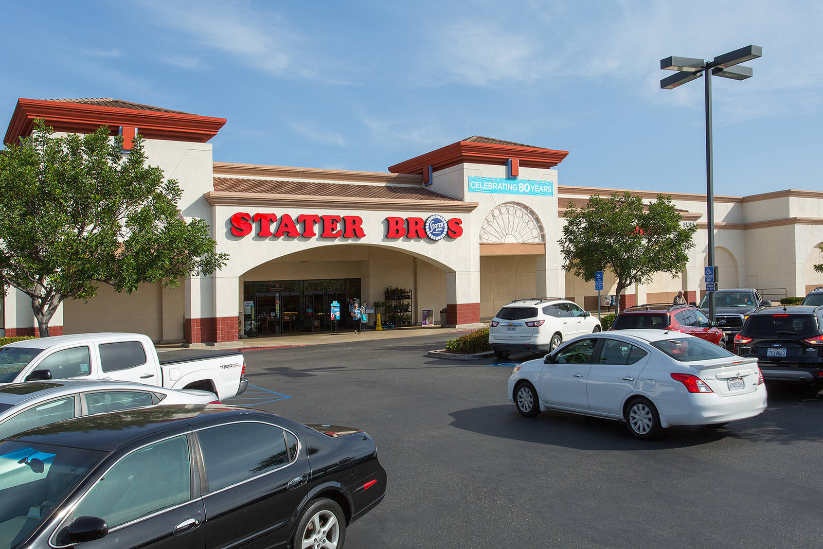 White car driving through full parking lot in front of State Bros