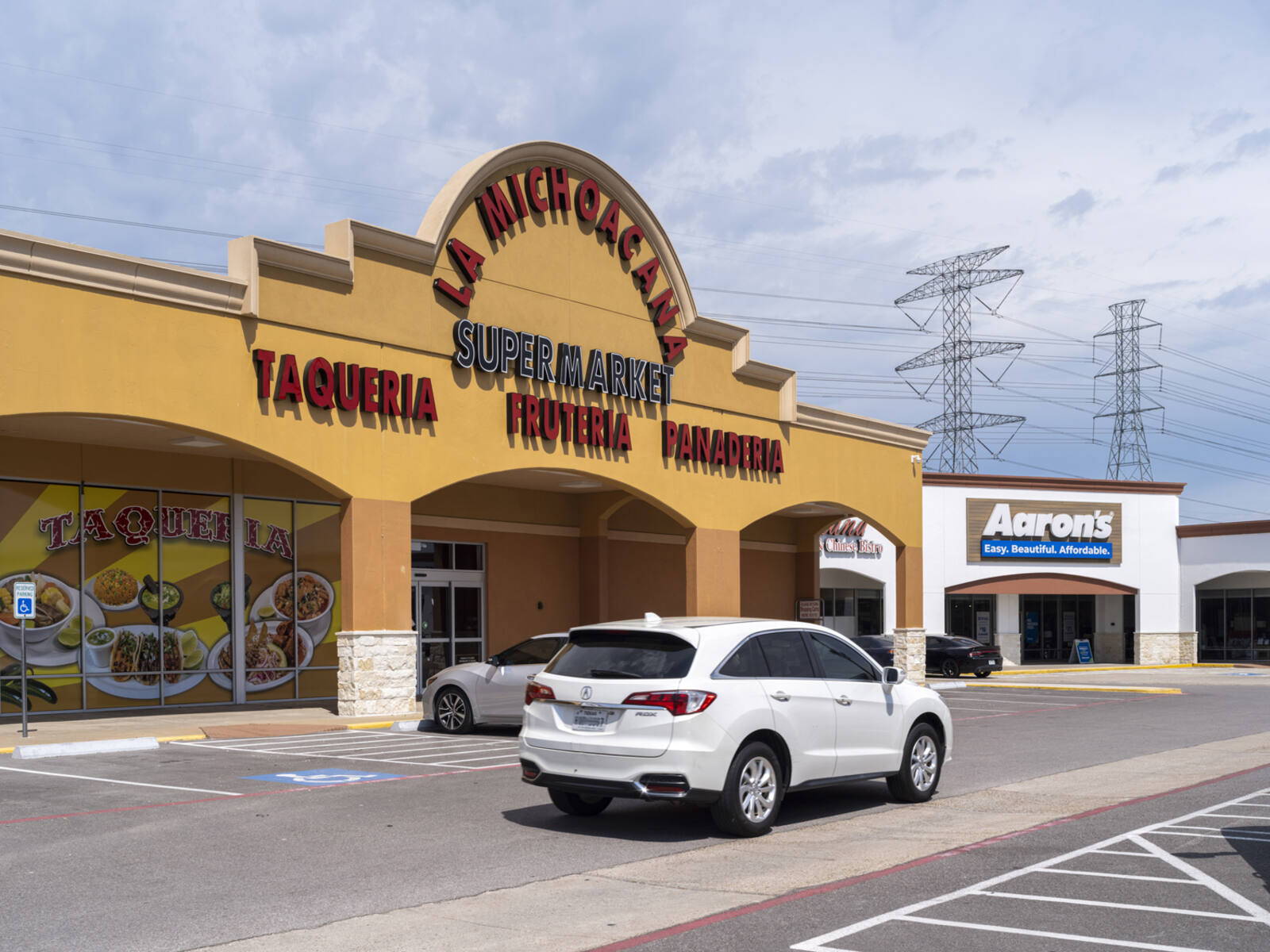 La Michoacana supermarket with white SUV car passing in front.