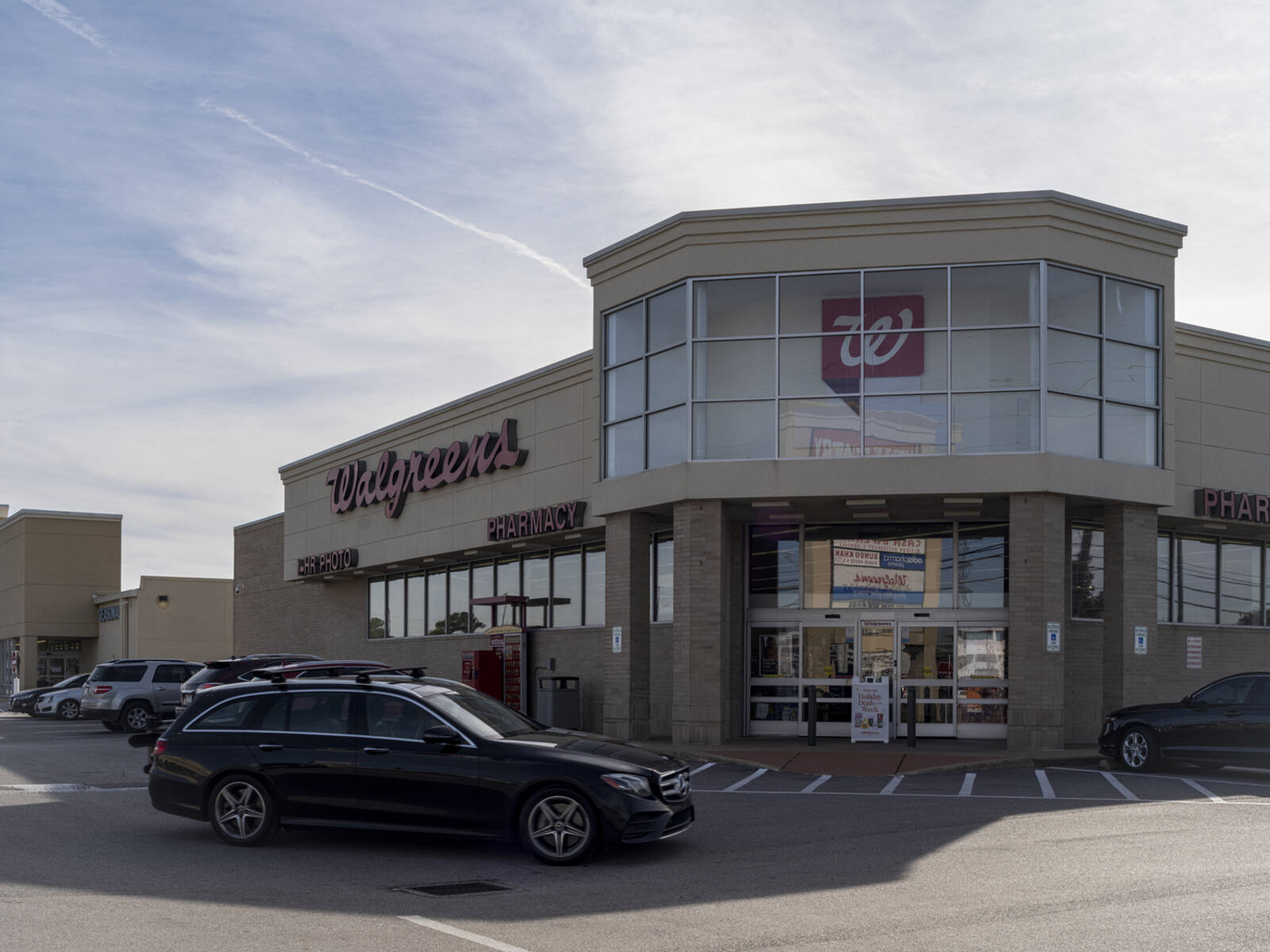 Black SUV passing the storefront of Walgreens.
