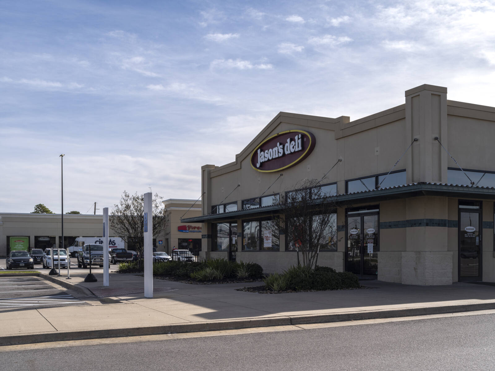 Jason's Deli with shrubs and planters in front and parking lot behind it.