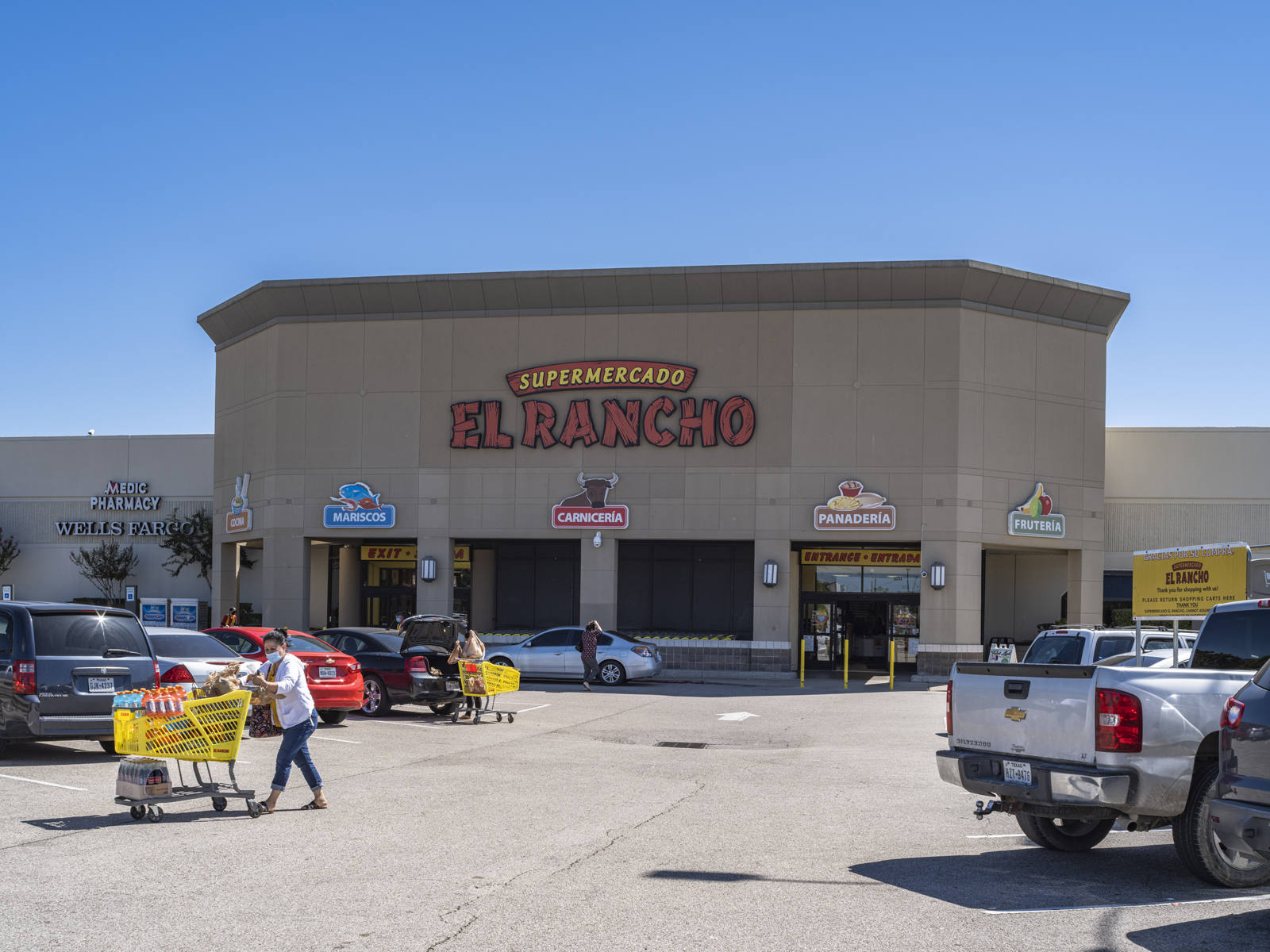 Customers with carts in parking lot of Supermercado El Rancho in Stafford, TX.