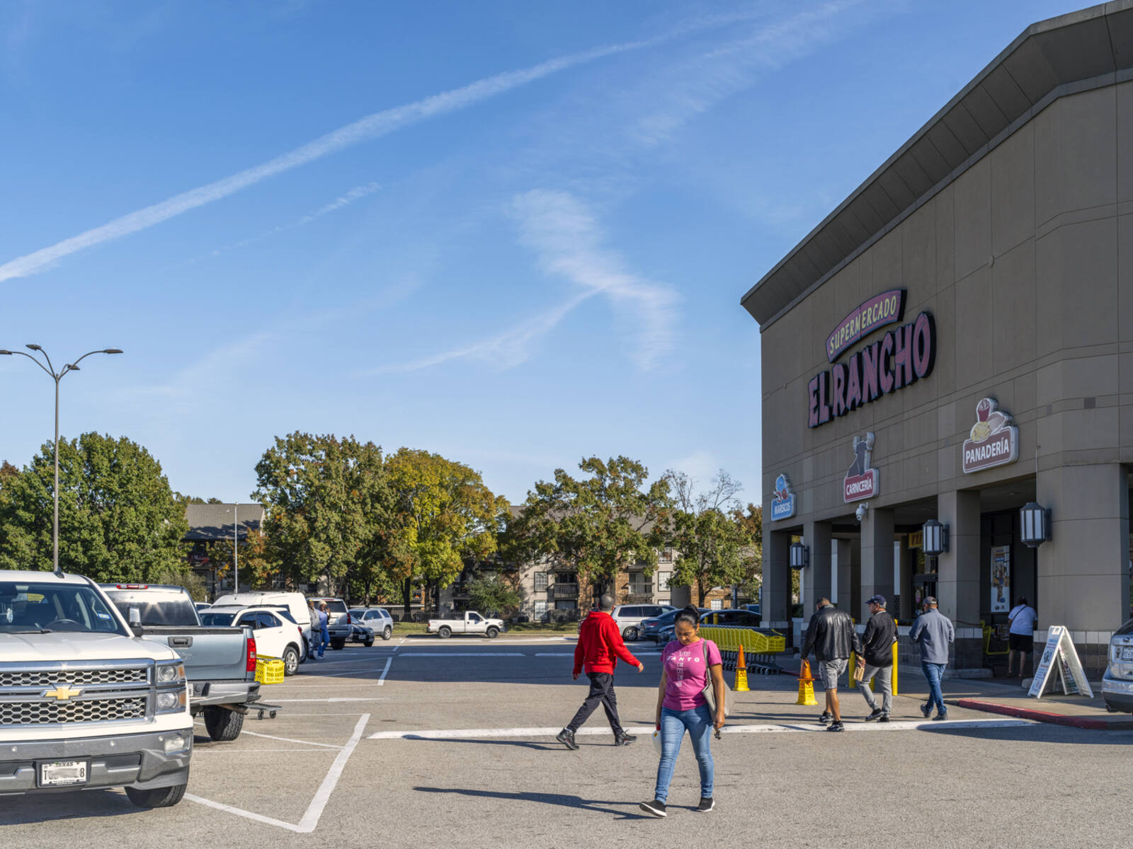 Busy entrance with pedestrians in front of El Rancho Supermercado.