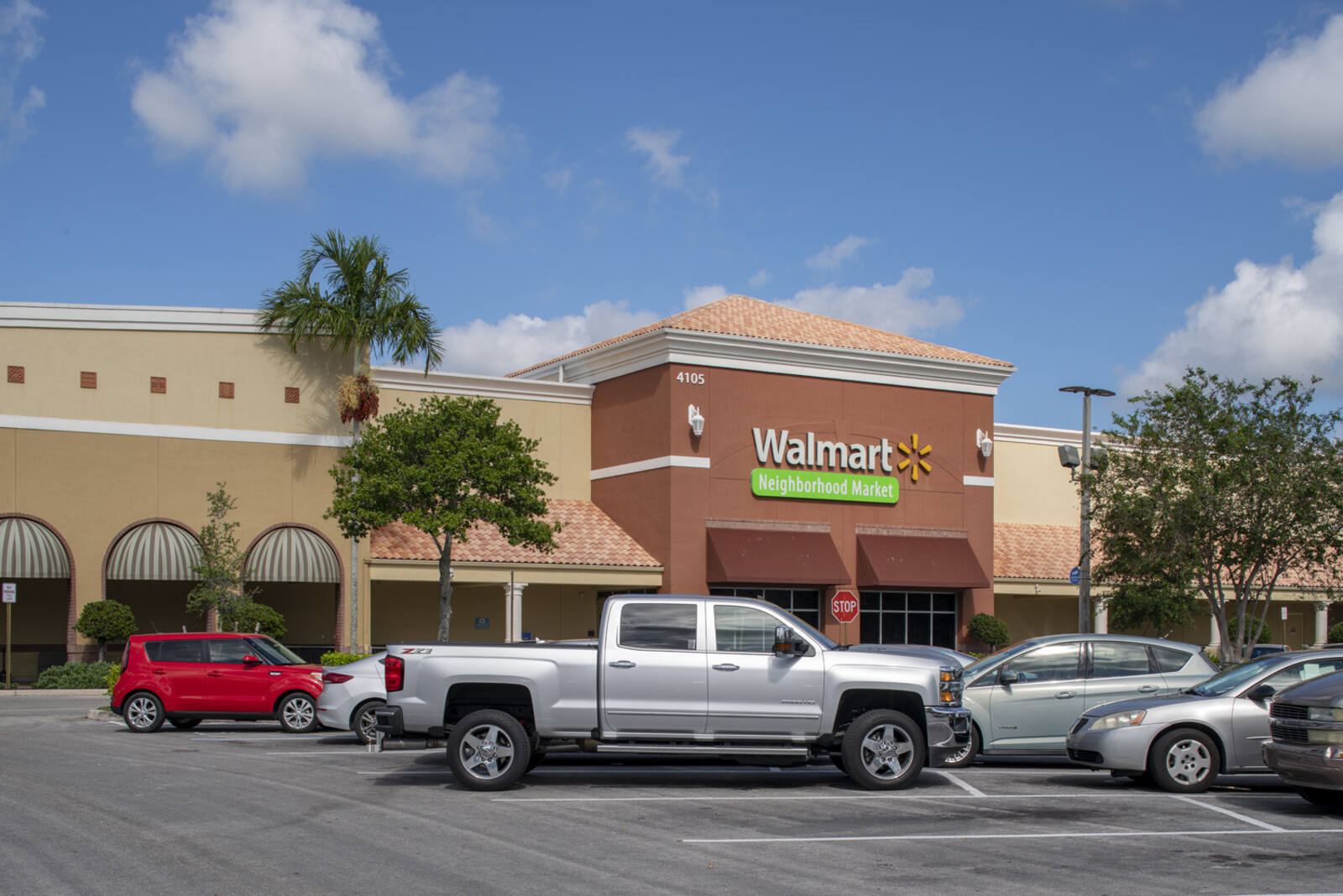 Walmart with small trees and palm trees in parking lot in Lake Worth, FL.
