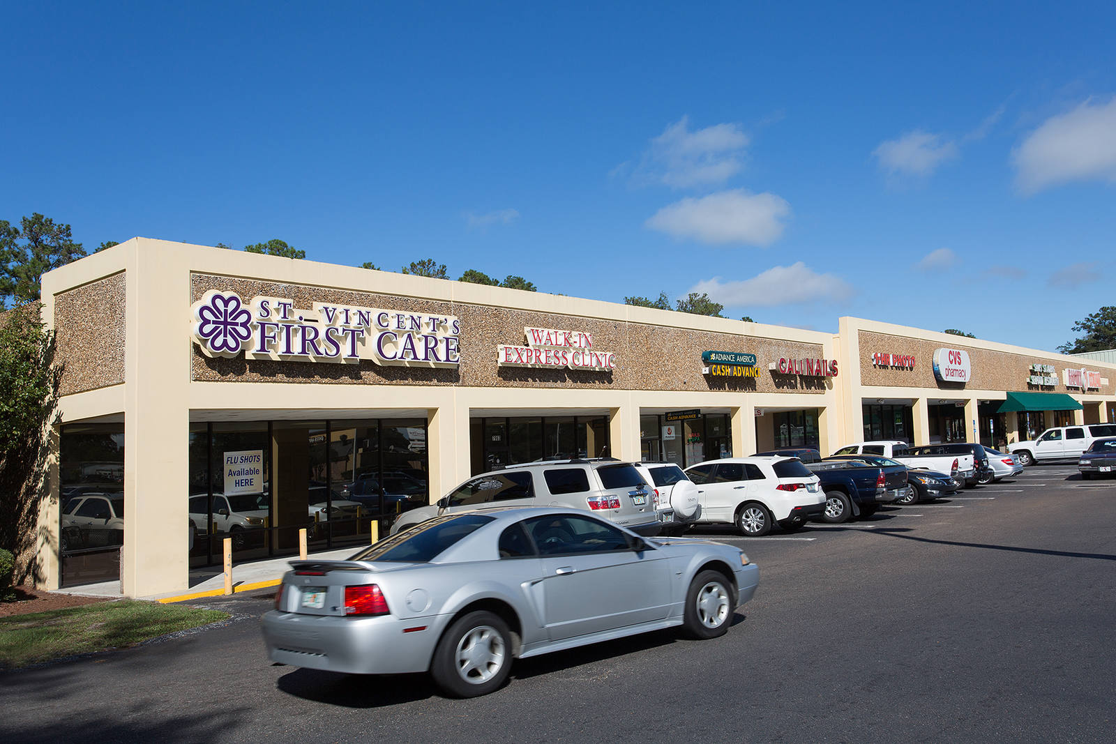 Grey car passing St. Vincent First Care and parking lot at Normandy Square.