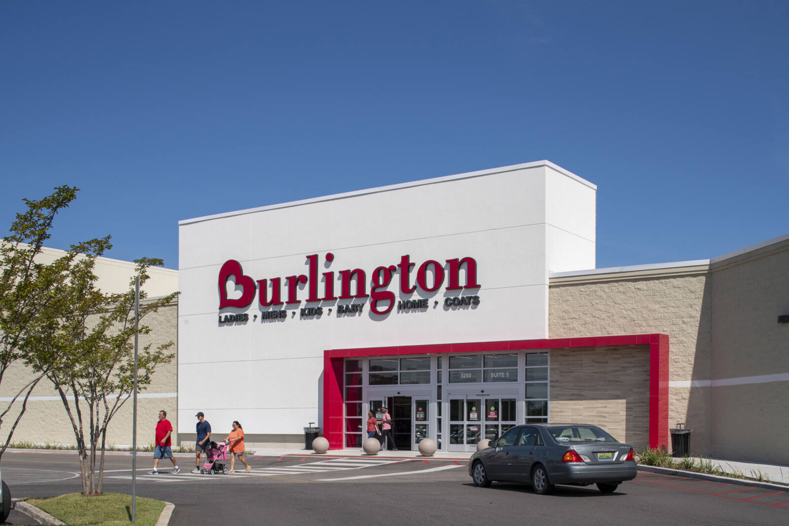 People walking out of Burlington and a car parked in front