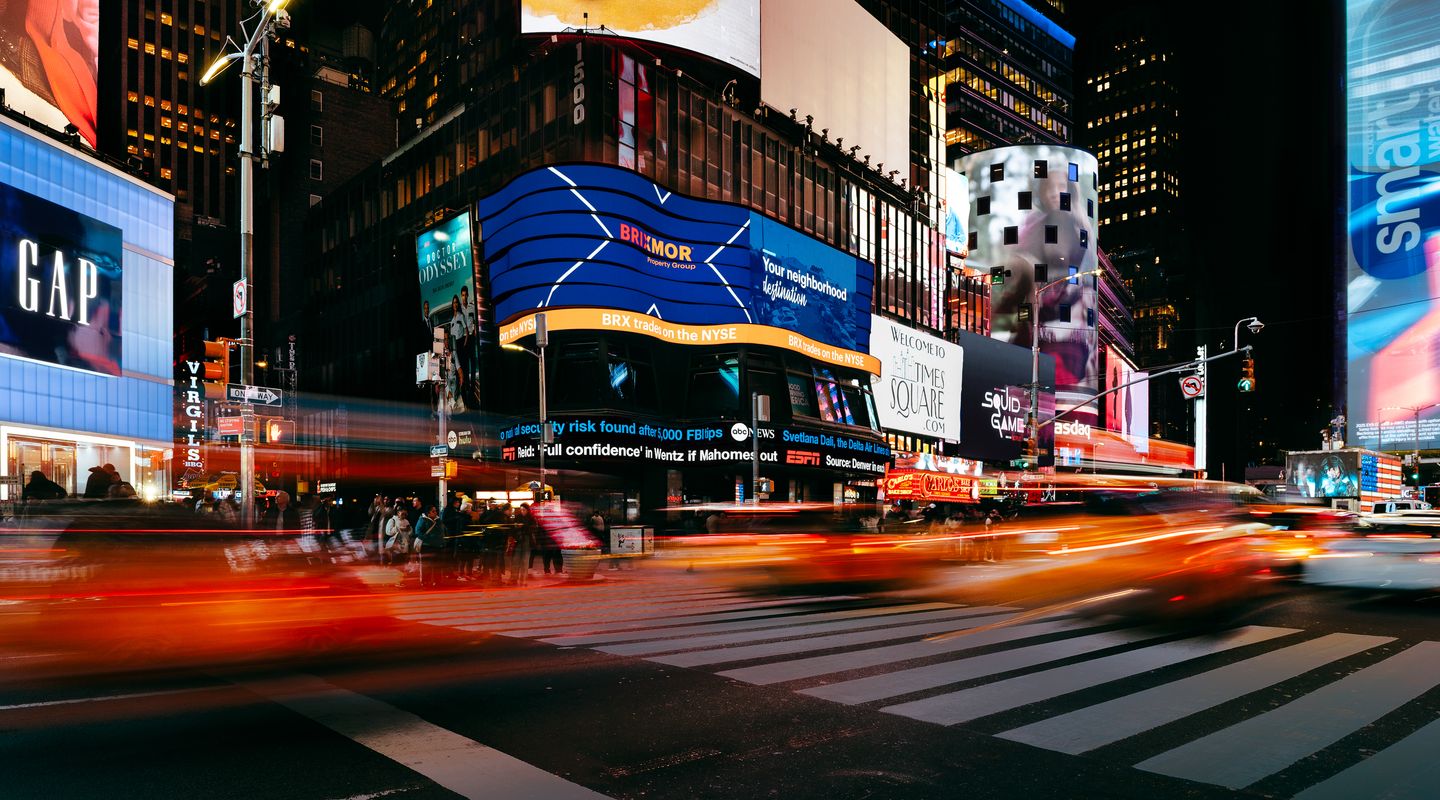 Brixmor featured on a NYSE digital billboard in Times Square in New York City at night with blurred car traffic in front