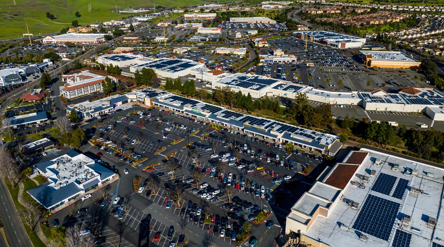 Aerial view of two open air shopping centers with solar panels on the rooftops