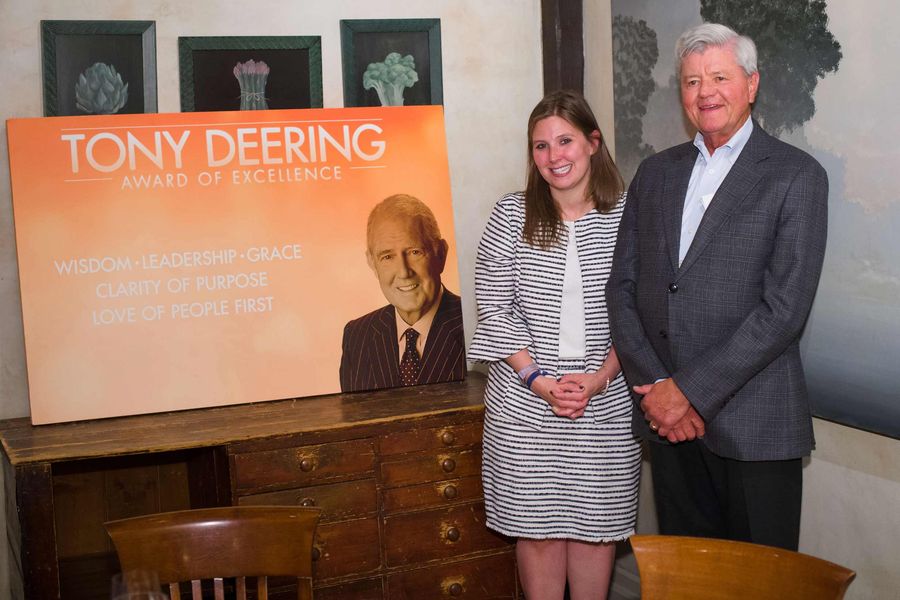 Woman and man standing beside a poster for Brixmor's highest employee honor, the Tony Deering Award