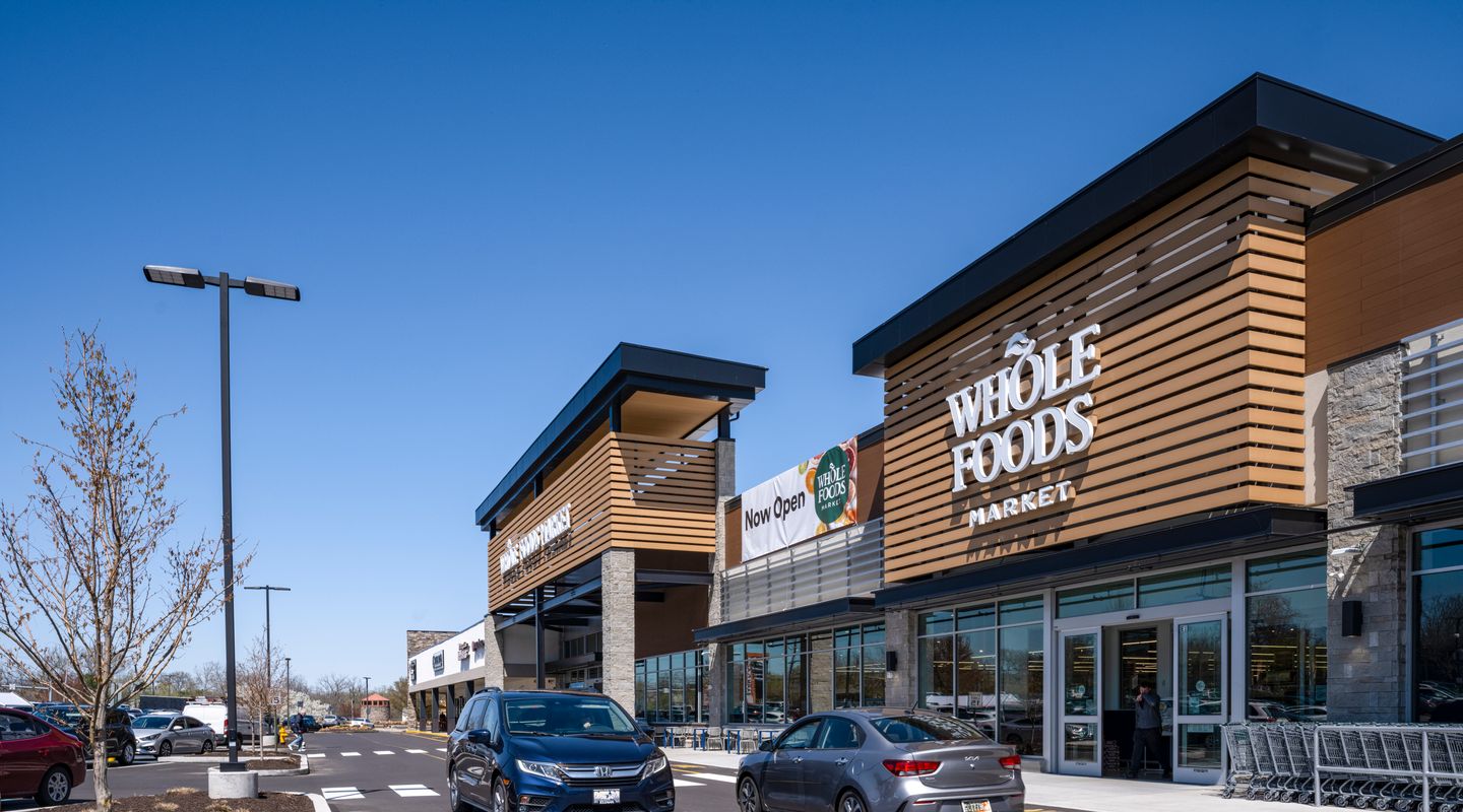 Two cars passing in the drive lane on front of Whole Foods Market at Barn Plaza shopping center