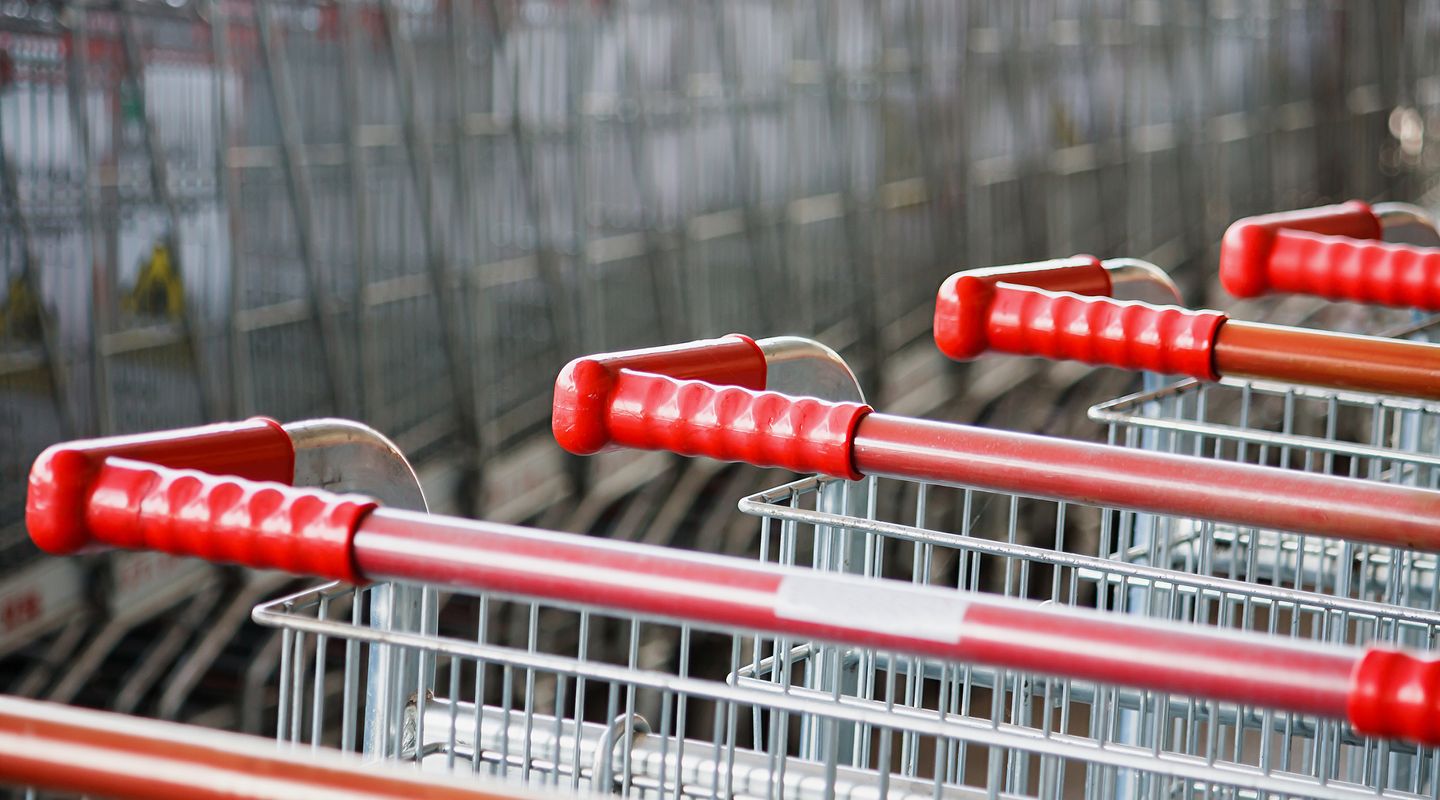 A close up view of the handles of multiple grocery shopping carts stacked together