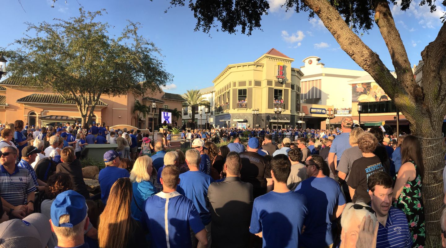 Large crowd of people looking at a stage in an open air shopping center