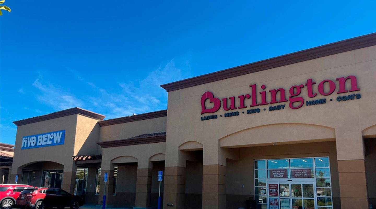 Burlington and Five Below at Vail Ranch Center in Temecula, CA, shown with warm earth‑tone architectural finishes, prominent red and blue signage, wide pedestrian walkways, and a partially filled parking lot beneath clear sunny skies.