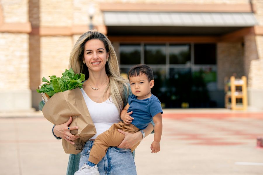 Woman holding a grocery bag and a young child