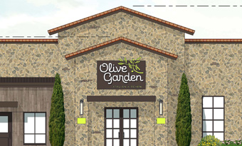 Architectural rendering of an Olive Garden restaurant at Wynnewood Village in Dallas, TX, featuring a stone façade with Mediterranean‑inspired detailing, clay tile roof accents, tall evergreen landscaping, and a prominent branded entryway.